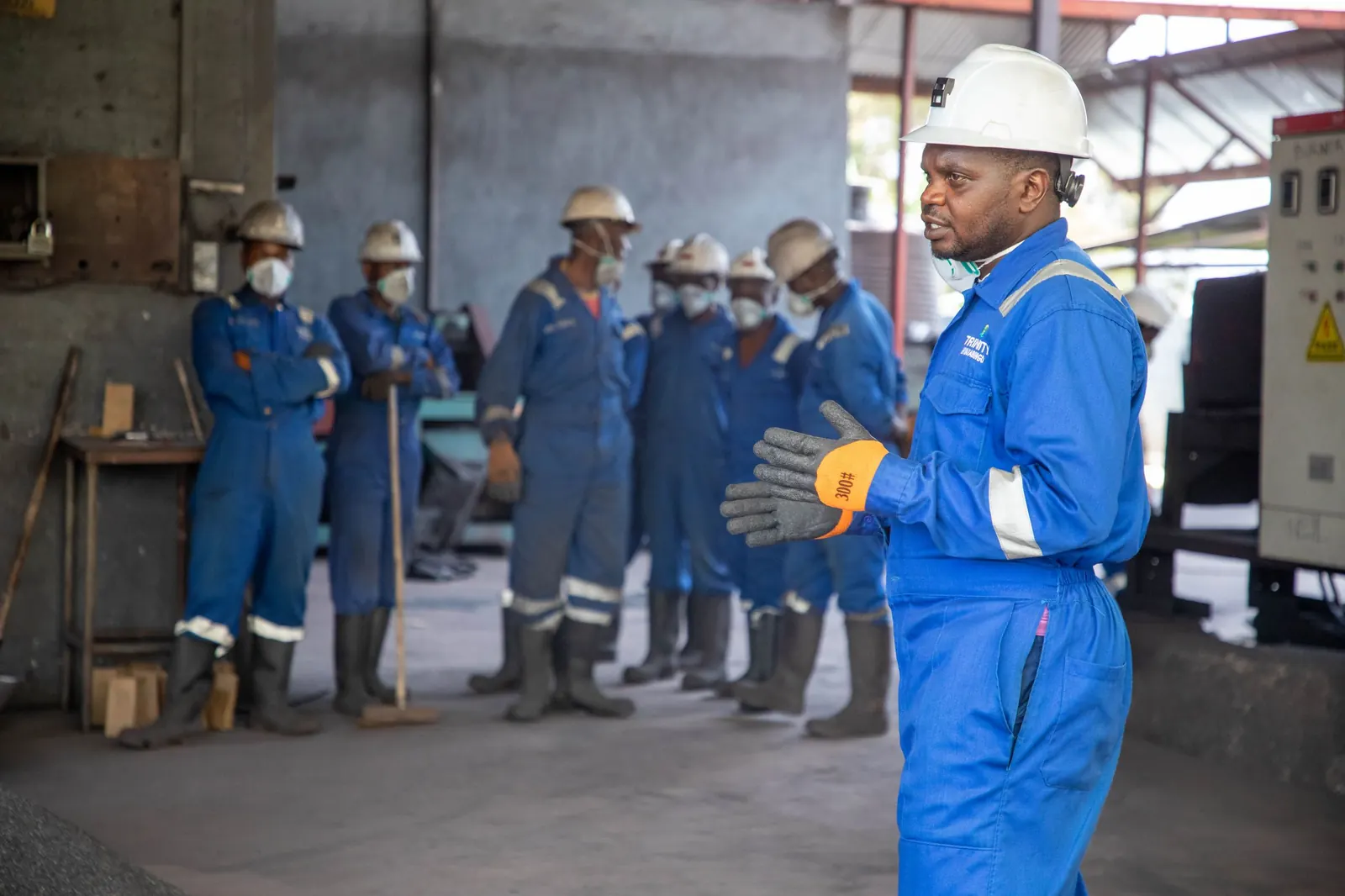 Instrutor orienta uma equipe de operadores uniformizados em uma área industrial